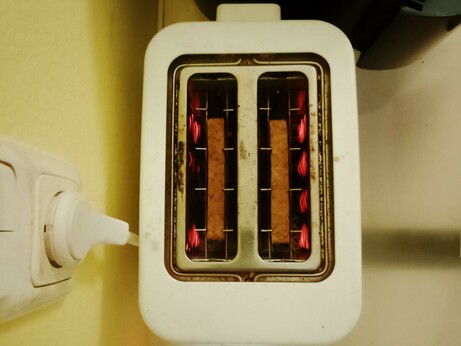 Filaments glow as toast toasts in the toaster, round side down.