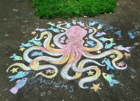 A chalk drawing of an octopus surrounded by brightly coloured fish on a path in a Glasgow park.
