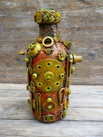 This image features a bottle that has been transformed into a compelling piece of steampunk-style art. Dominating the scene, the bottle is intricately adorned with an assortment of small mechanical components—gears, springs, bolts, and screws—all arranged with meticulous care. These metallic elements, some brass-colored and others with a more muted, rust-toned patina, create a textured and tactile surface that invites closer inspection.

The bottle itself shows a warm, earthy base color beneath the metallic embellishments, blending hues of orange, brown, and copper. This color palette enhances the antique and industrial vibe typical of the steampunk aesthetic. The bottleneck is wrapped in a thick, woven cord that adds a rustic yet deliberate finish to the piece, giving it a handcrafted feel. The backdrop, a rough wooden surface with visible grain, contrasts with and highlights the bottle's mechanical intricacies, grounding the artwork in a natural, raw environment.

Artistically, this creation evokes themes of invention and the fusion of organic and mechanical life, hallmarks of the steampunk genre, which melds 19th-century industrial steam-powered machinery with fantasy or speculative technology. Symbolically, this transformation of a mundane bottle into a miniature machine-like relic could suggest ideas about recycling, the beauty of repurposing objects, or the potential for hidden complexity within the everyday.