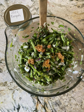 Dots of golden Rempah paste on thinly sliced green beans with minced green purslane. The fermentation is in a clear batter bowl. A few white shallot bits are visible.