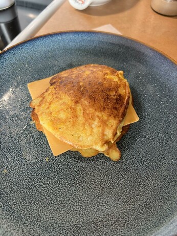 Photo of a stack of corn cakes on a blue plate, a slice of cheddar cheese between the two cakes.