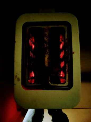 Filaments glow as toast toasts in the toaster, round side down.