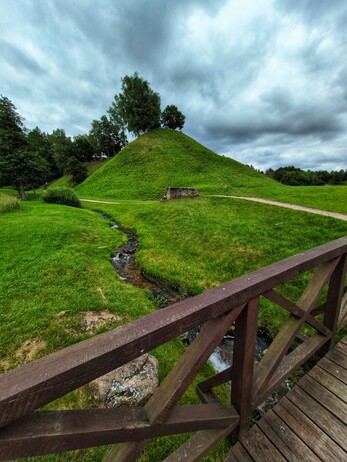 The now empty green hill, with some trees on it.