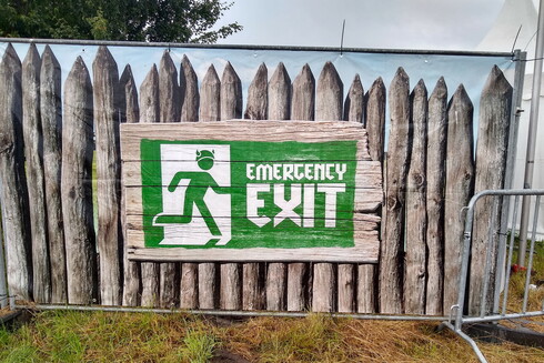 A green emergency exit sign. The figure on it is wearing a viking-style helmet with horns.