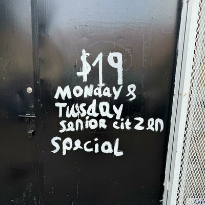 Hand painted letters on a black door: "$19 Monday & Tuesday Senior Citzen (sic) Special"