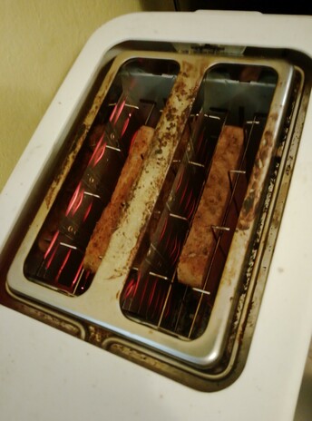 Filaments glow as toast toasts in the toaster, round side down.