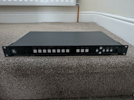 A picture of the device. It's a wide, flat piece of video equipment, looking somewhat like a DVD player. There are several large white buttons across the front of the unit.