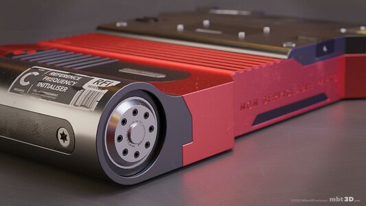 Red and dark grey metal component close up on a circular end with vent holes and a sticker saying Reference Frequency Initialiser.
