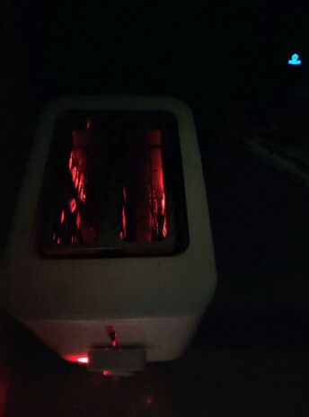 Filaments glow red as toast toasts in the toaster, round side down.
Headphones glow blue in the background.