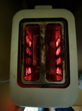 Filaments glow as toast toasts in the toaster, round side down.