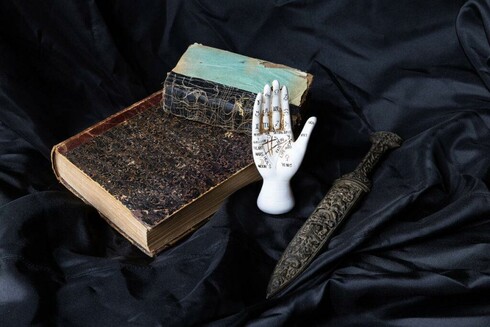 a selection of items - book, a dagger and a palmistry hand - from the Dark Secrets exhibition