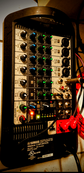 The photograph shot in 81A warm light, shows a Yamaha portable PA system, model Stagepas 400, with a black front panel featuring various controls and indicators. The panel includes eight channels, each with level knobs labeled "LEVEL 1-6" and "LEVEL 7/8," as well as input knobs for "LOW," "HIGH," and "REVERB." Each channel has an XLR input labeled "MIC" or "LINE." The panel also features a "REVERB TYPE" knob with "HALL" and "PLATE" options, a "MONO" switch, and a "MASTER" section with "EQ BOOST," "ECO," and "LEVEL" knobs. There are LED indicators for "FEEDBACK," "REVERB," and "POWER," along with a "LIMITER" section. The bottom of the panel displays the Yamaha logo, model number, and specifications, including "100-240V ~ 70W 50/60Hz" and "MADE IN CHINA." The device is connected to cables, with red and black connectors visible on the right side.

Provided by @altbot, generated privately and locally using Ovis2-8B

🌱 Energy used: 0.286 Wh