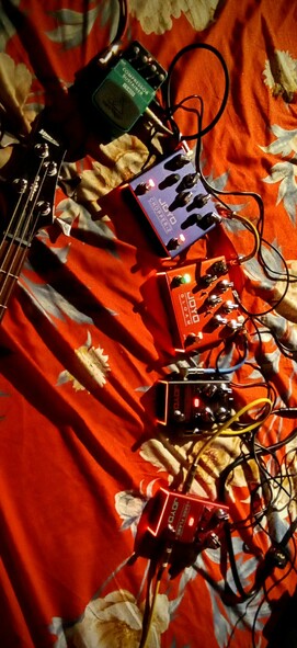 The photograph shot in 85F warming light, shows a collection of guitar pedals arranged on a red fabric with a floral pattern. The pedals are connected by various cables, creating a complex network. The pedals include a green "COMPRESSOR SUSTAINER," a blue "JOYO CHOPPERZ," a red "JOYO GLOOM," a black "Double Thruster," and a red "JOYO DARK FLAME." The pedals are positioned in a vertical line, with the Bass guitar headstock visible on the left side. The cables are of different colors, including black, yellow, and blue, and are connected to the pedals and the guitar. The lighting highlights the pedals and cables, creating a warm and vibrant atmosphere.

Provided by @altbot, generated privately and locally using Ovis2-8B

🌱 Energy used: 0.185 Wh
