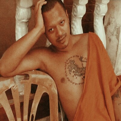 The cover for Hussain Bokhari's Possessions album on Mood Hut records, showing a man in a Buddhist monk style orange robe with a tattooed chest reclining on a plastic chair, hand resting on head. Background features white railings.