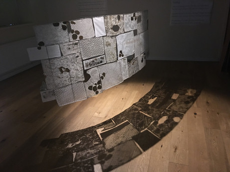 hanging sculpture, embroidery and lace  in the shape of stacked squares. resembling a drystone wall