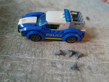 A Lego police car with four plastic caltrops next to it.