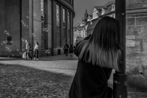 Girl making soap bubbles, street photo, Prague