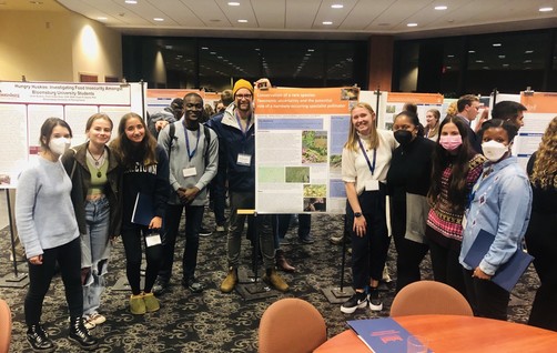 9 members of the Martine Lab at Bucknell University gathered around a student research poster at a campus poster session