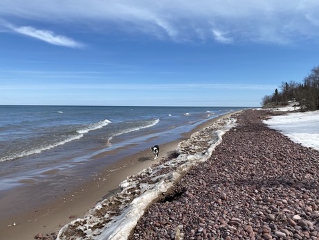 View down the beach at eagle river Michigan, early spring, band of ice between sand and cobbles. 