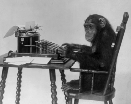 old black and white photo of a chimpanzee sitting at a very old manual typewriter, his hands are up near the keys. the photo is taken from the side and he is looking away from the typewriter off to the left of the camera.