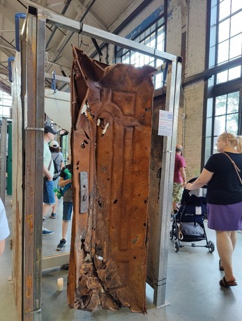 A metal door from a house in Ukraine, buckled and riddled with holes from a bomb blast during the war of aggression imposed by Russia. 