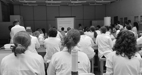 A lab full of students in lab coats watching class