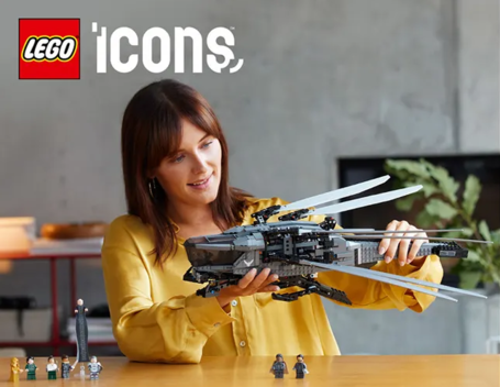 A woman with a dazed look on her face plays with a LEGO ornithopter