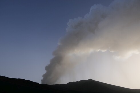 A grey column of ash and gas rising above Mt Etna produced by a paroxysm in the Voragine crater